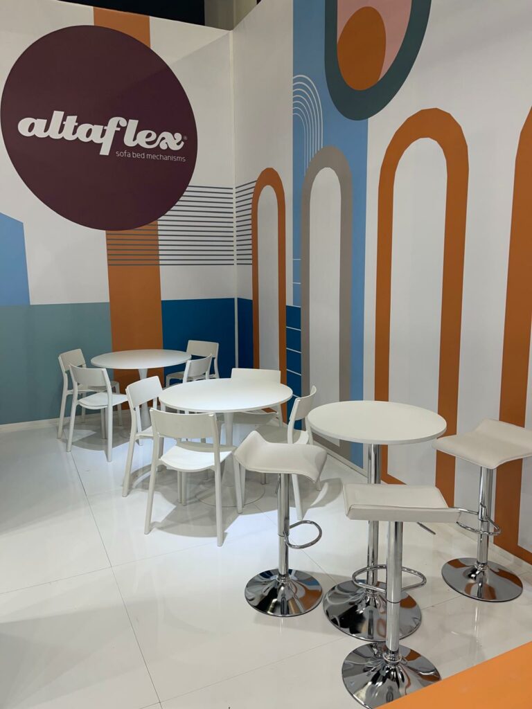 Area accoglienza dello stand Altaflex Interzum 2023 - Zona relax con tavolini rotondi e sedute confortevoli per incontri business