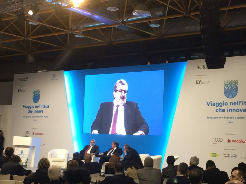 Scena principale della conferenza con palco per gli espositori, grande schermo sullo sfondo e attrezzature multimediali per audio e video